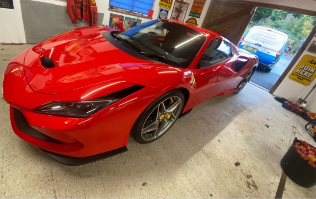 RS Connect van parked behind a red Ferrari in a garage, while an engineer installs a vehicle tracker on the Ferrari.